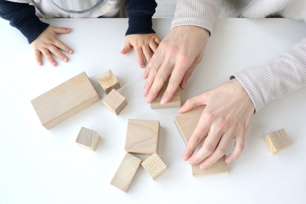 親子で木の積み木に触れる手元
